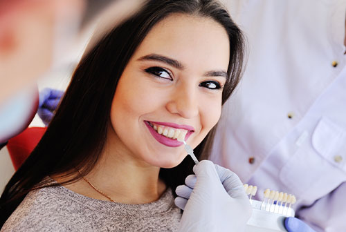 A woman receiving dental care, sitting in a dentist s chair with a smiling expression, while a dental professional works on her teeth.